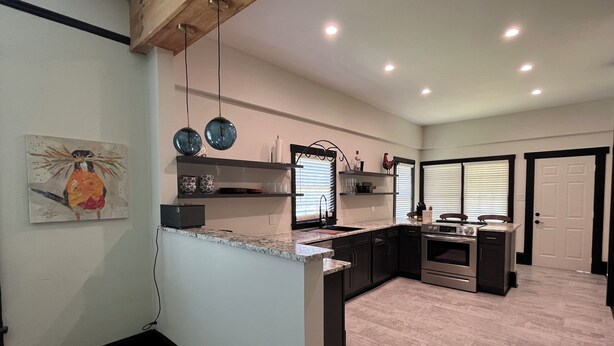 A modern kitchen with a granite countertop, stainless steel appliances, and a black and white color scheme.