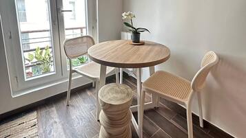 Un coin repas avec une table ronde en bois, deux chaises blanches et une petite plante en pot.