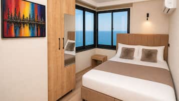 Ein Schlafzimmer mit Bett, Kleiderschrank, Nachttisch, einem Gemälde und einem großen Fenster mit Aussicht.