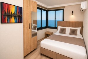 A bedroom with a bed, a wardrobe, a nightstand, a painting, and a large window with a view. - Iotape Hotel Antalya (Alanya)