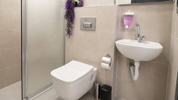 Un baño moderno con inodoro, lavamanos y ducha.