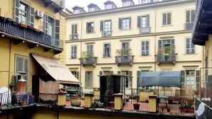 Une cour bordée de bâtiments jaunes, dotée de balcons et d’un petit espace abrité.