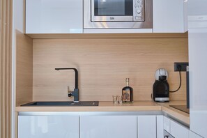 Eine moderne Küche mit integriertem Mikrowellenherd, einer Kaffeemaschine und einem Spülbecken.