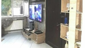 Un salon avec un téléviseur, un meuble en bois et un radiateur.