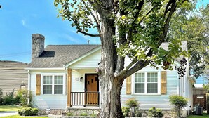 A single-story house with a stone chimney, a front porch, and a large tree in the front yard. - “Delightful Decor” & “SO CLOSE” to Beech Bend, WKU, Caves, & Corvette Museum! (Bowling Green)