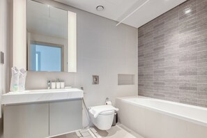 Features a sleek vanity, sink, and spacious bathtub, along with a shower area.