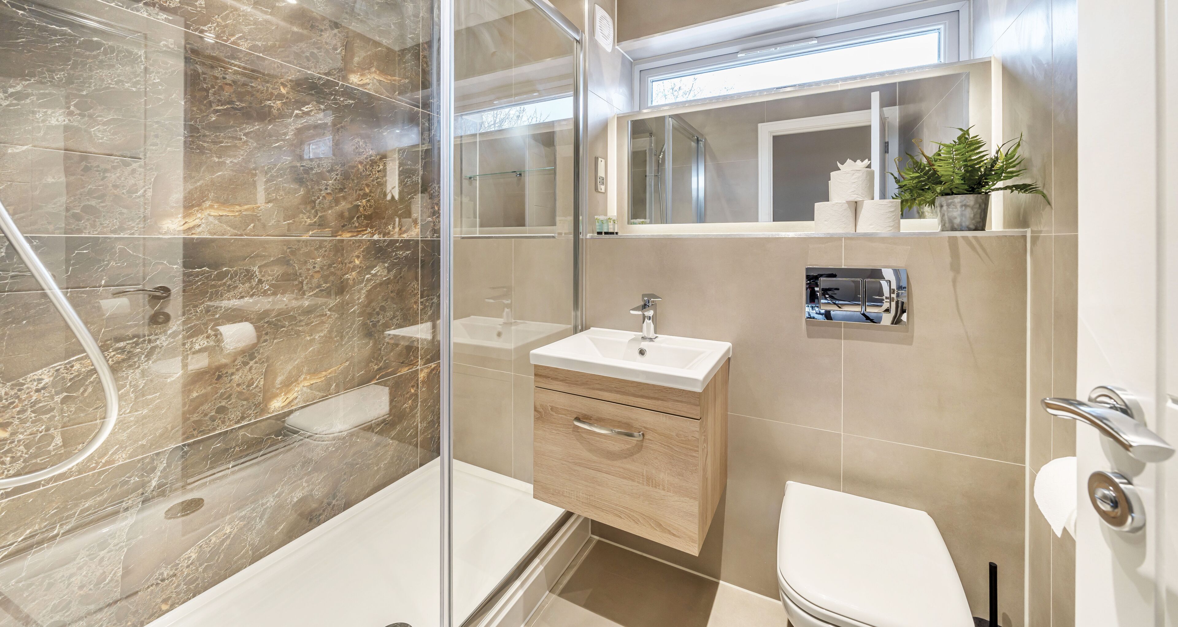 Ein modernes Badezimmer mit einer Duschkabine, einem Holzkosmetikschrank mit Waschbecken und einer Toilette.