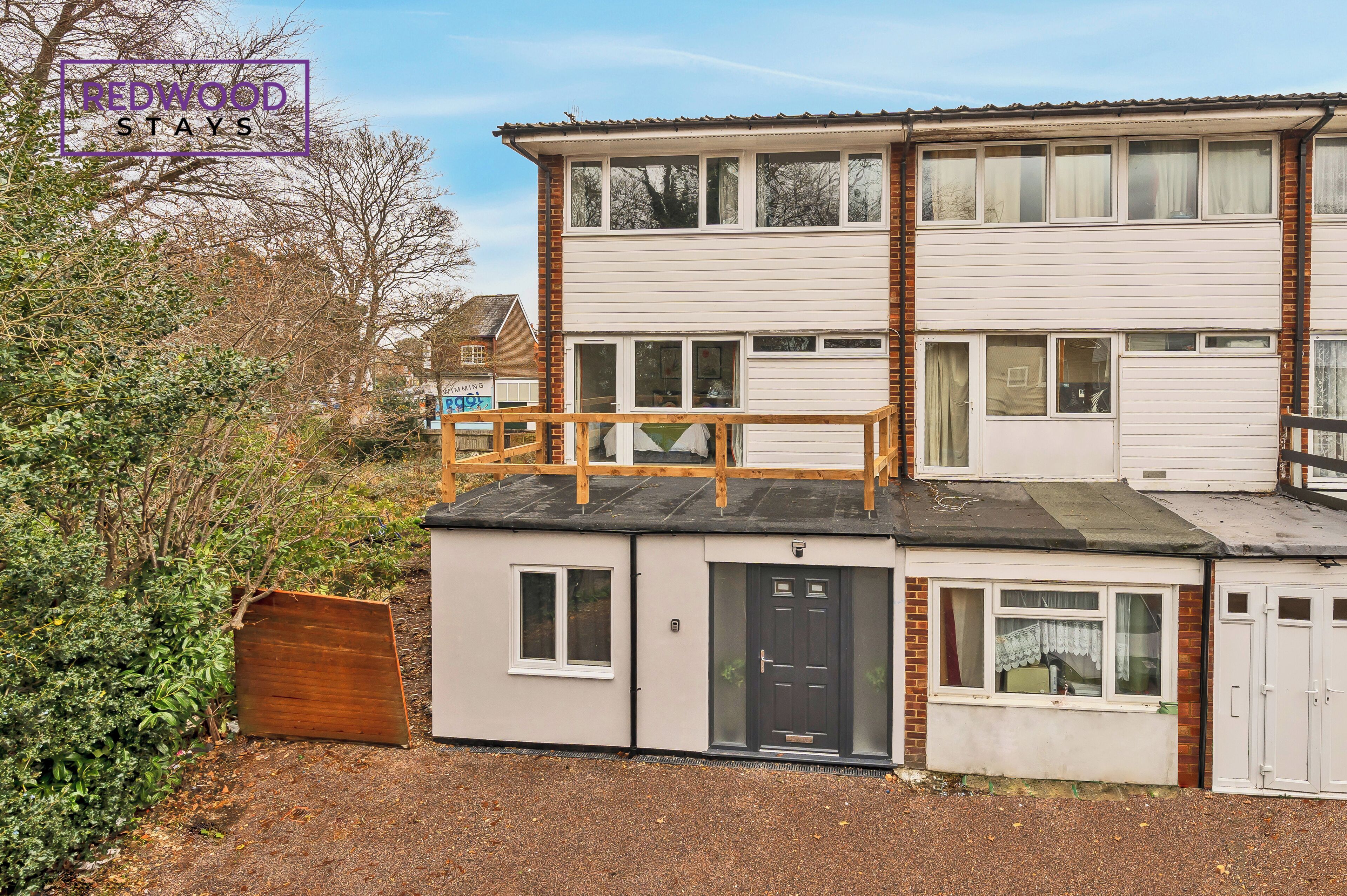 A two-story building with a flat roof, a balcony, and a small attached garage.