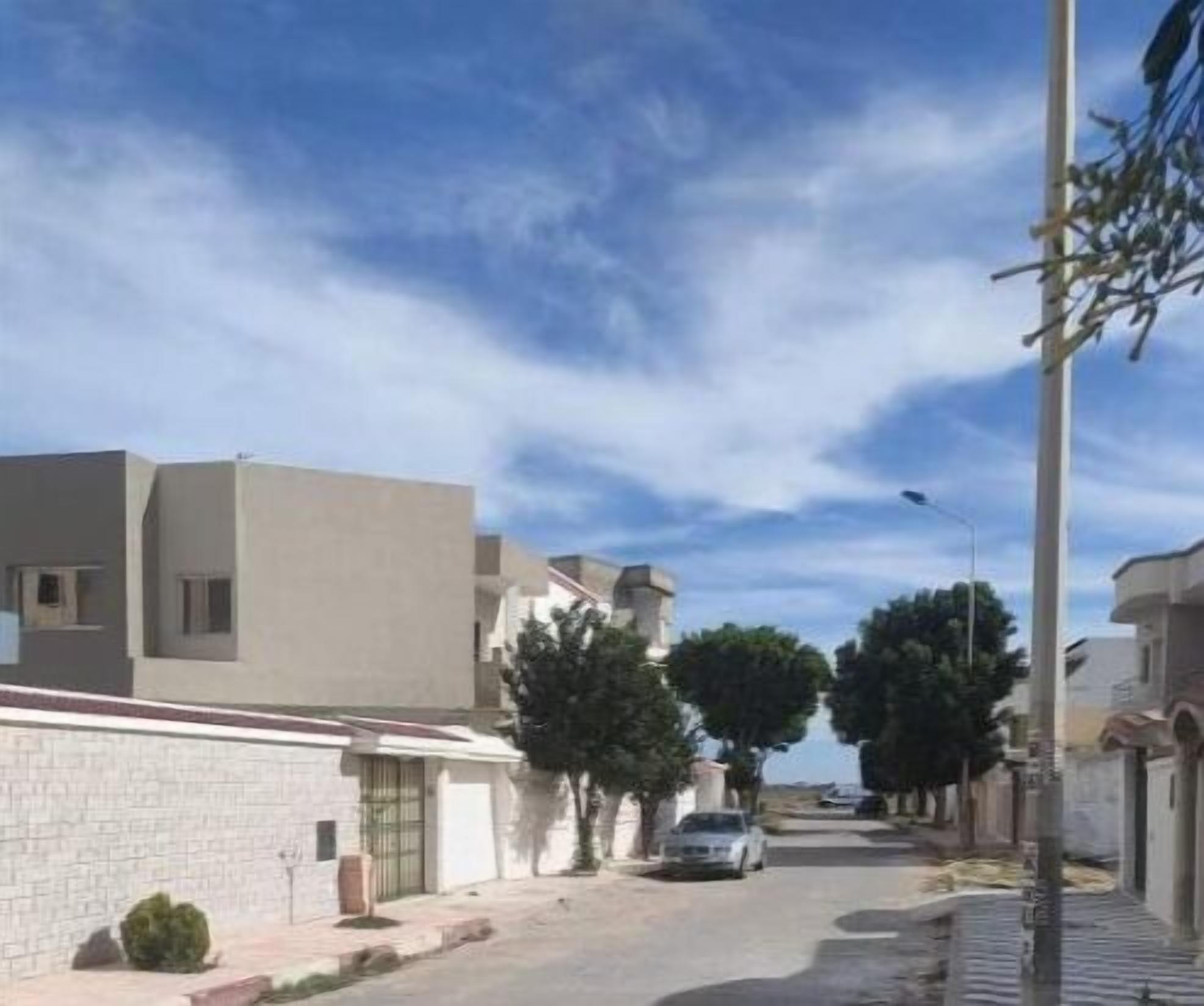 A residential street with modern houses, a clear sky, and a parked car.
