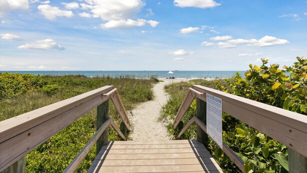 Une promenade en bois mène à une plage où un panneau indique la zone où l'accès est interdit.
