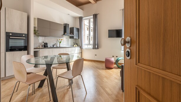 A modern kitchen with a glass dining table, wooden flooring, and built-in appliances. - Casa Finocchiaro by Wonderful Italy (Palermo)