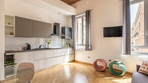 A modern kitchen with grey cabinets, a glass dining table, and a sofa with colorful rings. - Casa Finocchiaro by Wonderful Italy (Palermo)