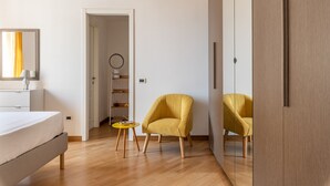 A modern hotel room with a bed, two yellow armchairs, a small round table, and a wardrobe. - Casa Finocchiaro by Wonderful Italy (Palermo)