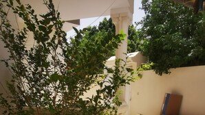 Un patio con una jardinera de piedra, piso de baldosas y una pared blanca con columnas.
