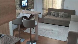 Una sala de estar con un sofá, una mesa de centro y un televisor instalado en una pared de piedra.