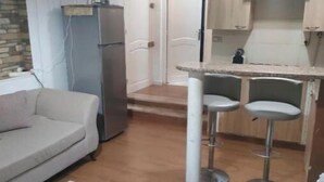 Un espacio habitable compacto con kitchenette, un sofá y un pequeño comedor.