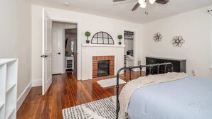 A bedroom with a bed, a fireplace, a ceiling fan, and a wardrobe. - Historic Ludlow Suites (Covington)
