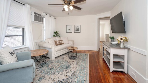 A living room with a sofa, coffee table, and a TV on a stand. - Historic Ludlow Suites (Covington)