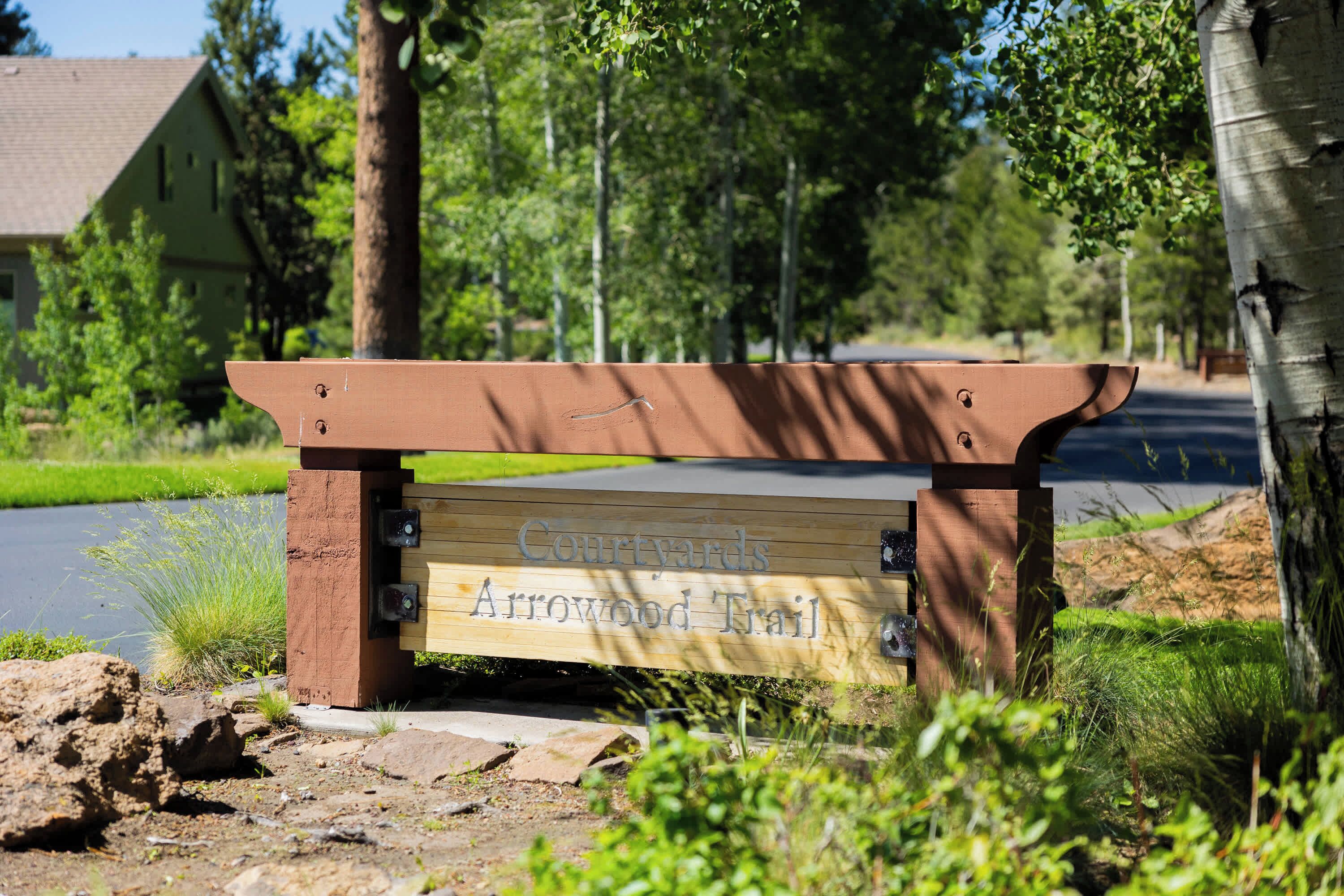 Un banco de madera con un letrero que dice 'Courtyards Arrowood Trail'.