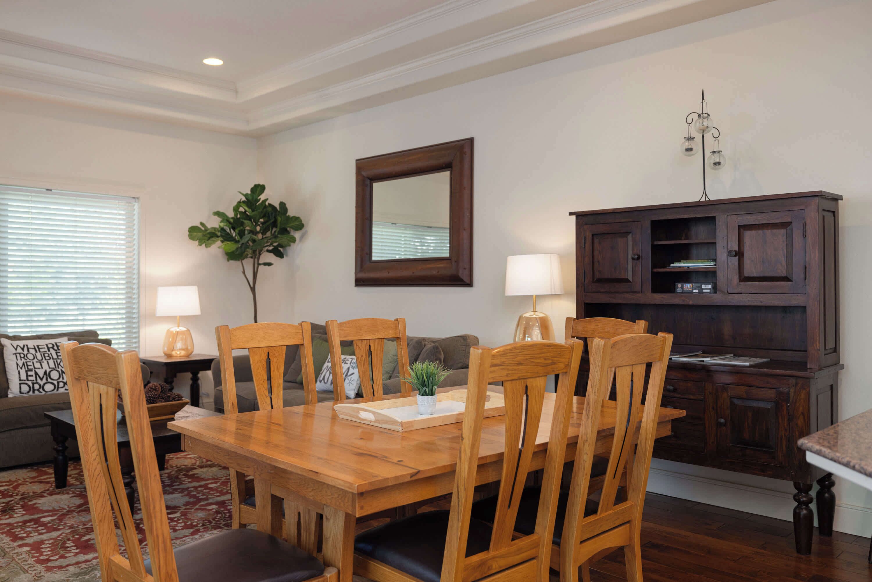 A dining area with a wooden table and chairs, a dark wooden cabinet, and a mirror on the wall.