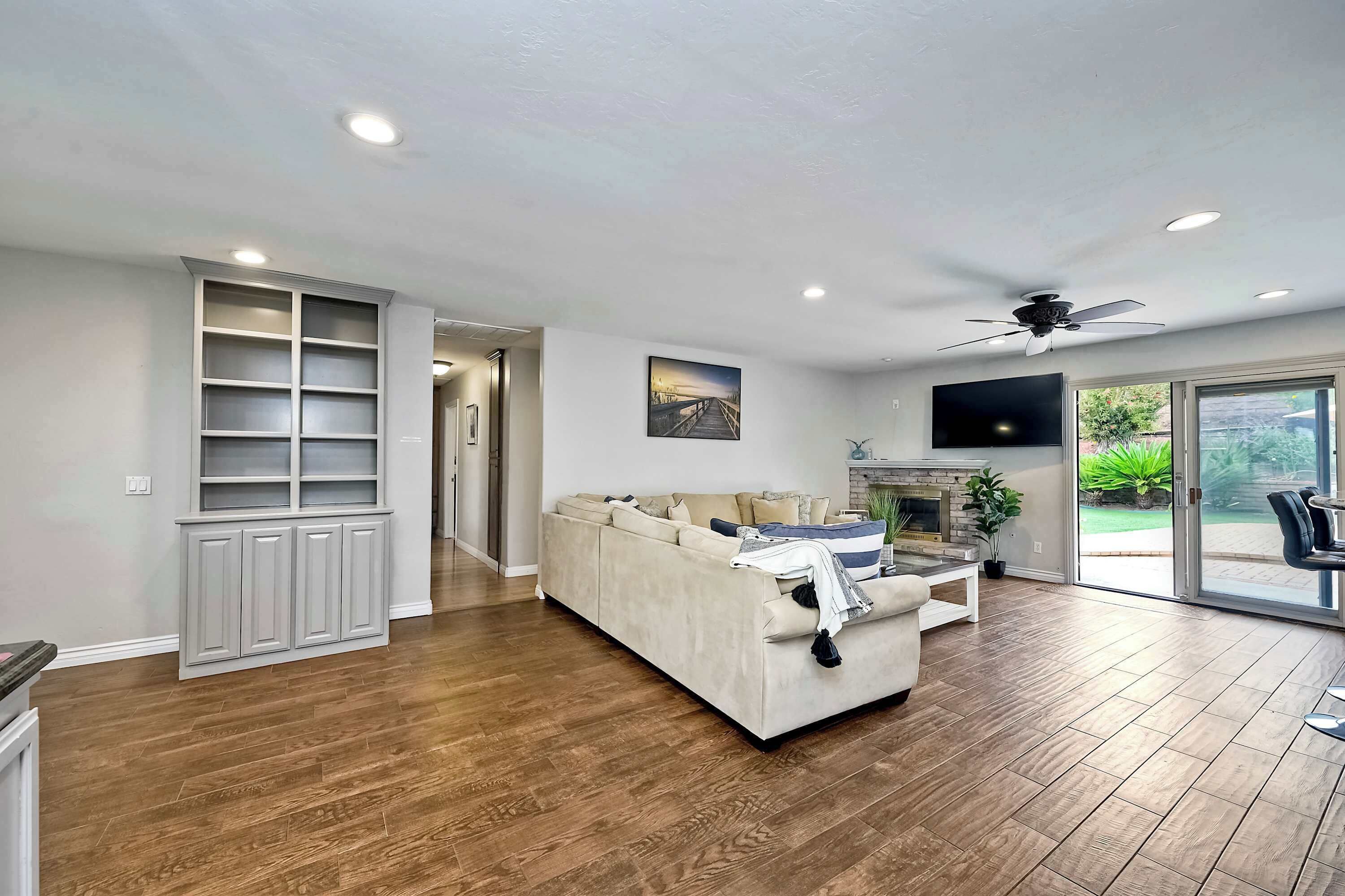 A spacious living room with a sofa, built-in shelving, a fireplace, and a TV.