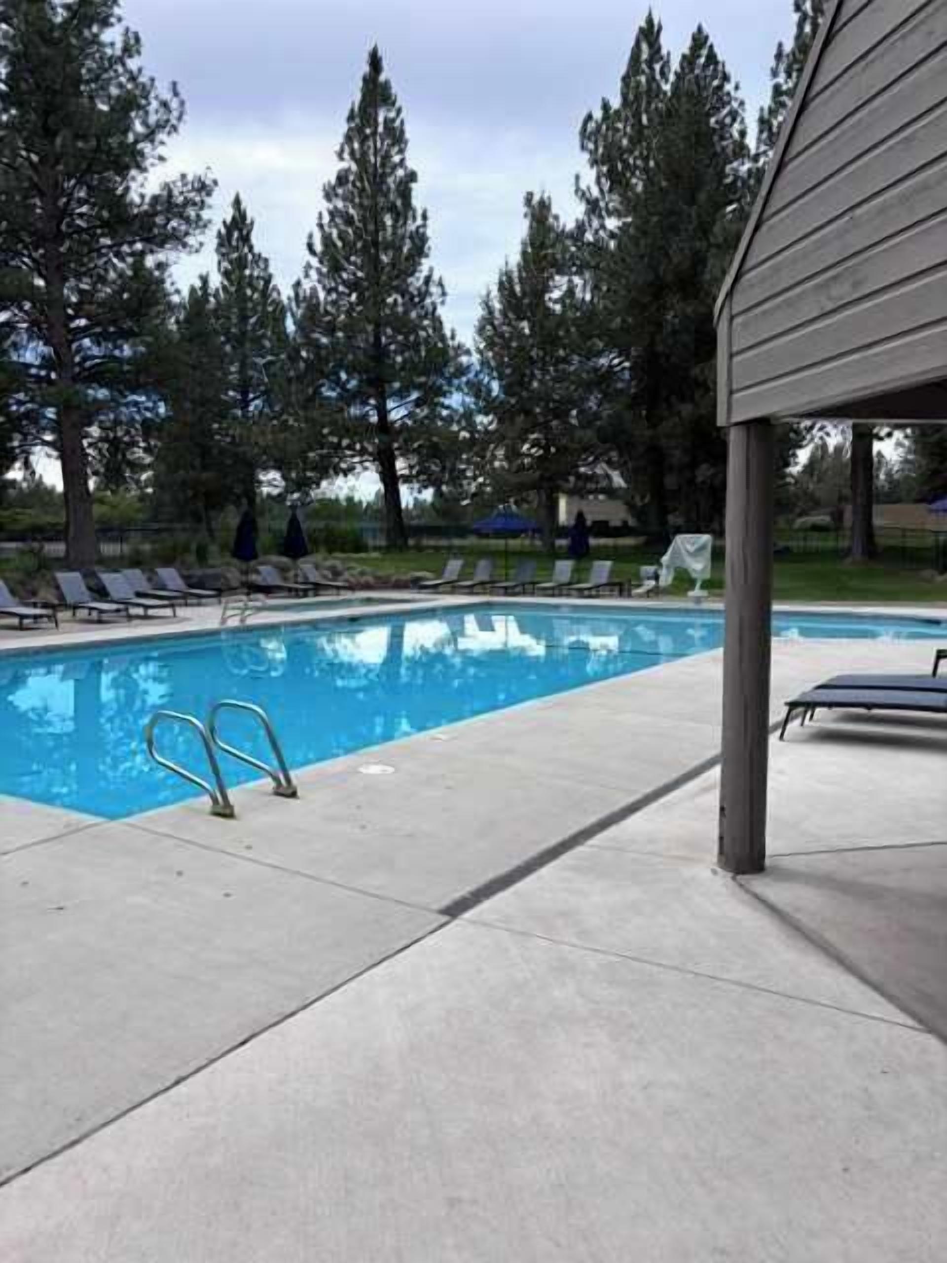 Una piscina con sillones de descanso y una zona cubierta.