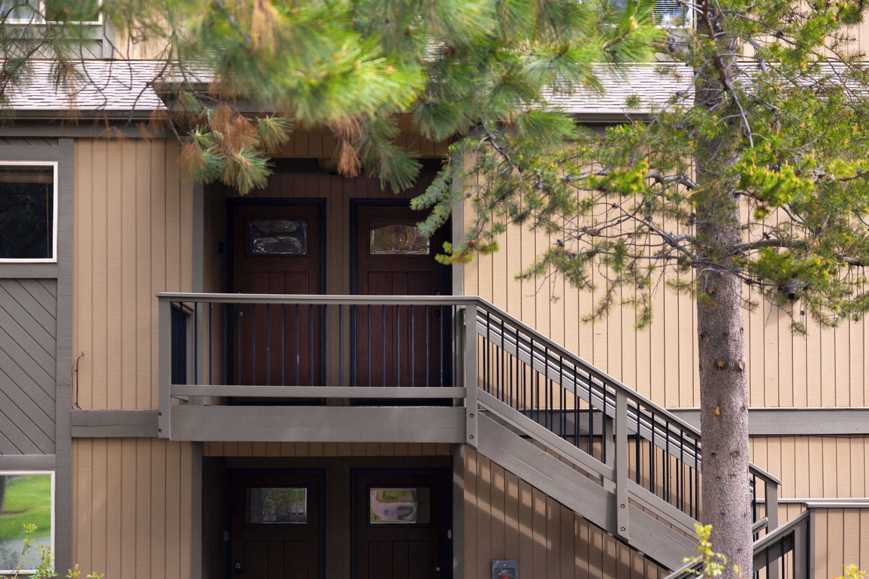 A two-story building with a balcony and a tree in the foreground.