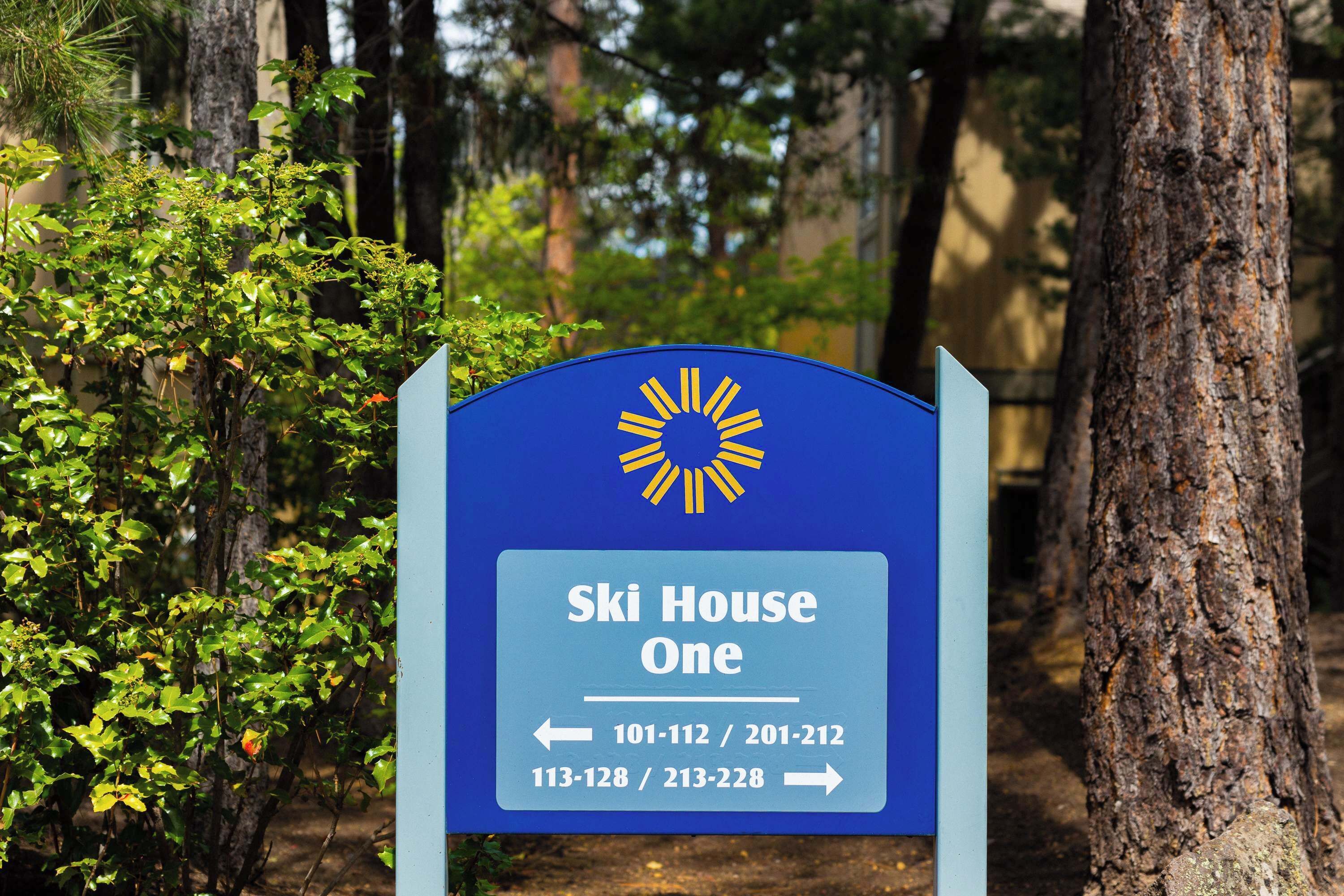 A sign for 'Ski House One' with directional arrows and phone numbers.