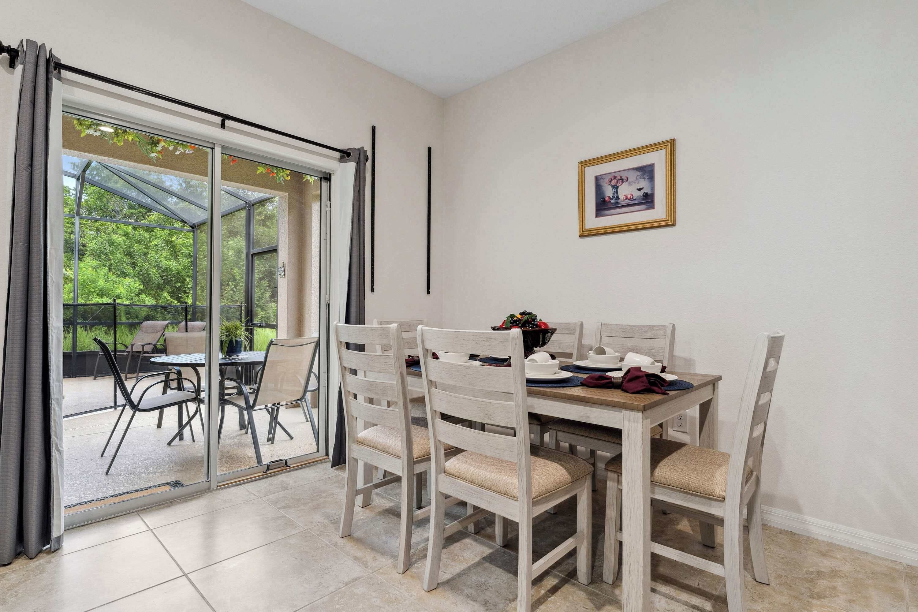 A dining area with a table and chairs, a glass door leading to an outdoor patio, and a framed picture on the wall.