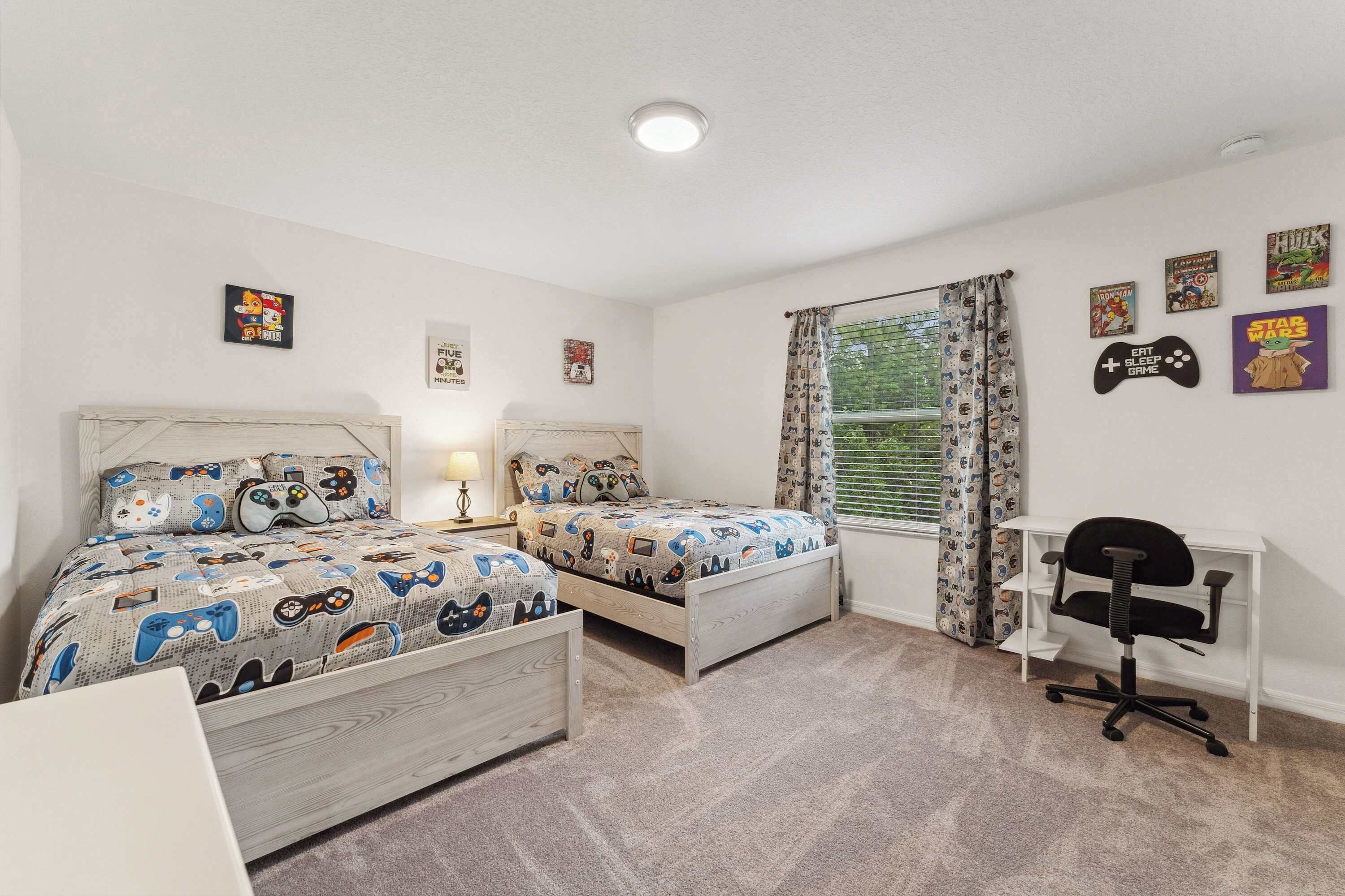 A bedroom with two beds, a desk, and a chair.