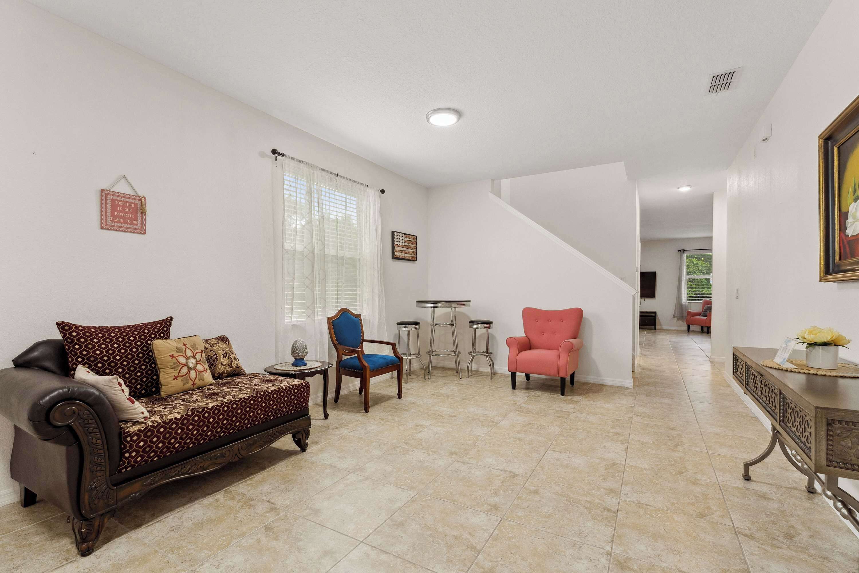 A living room with a sofa, armchairs, a small table, and a staircase leading to another room.