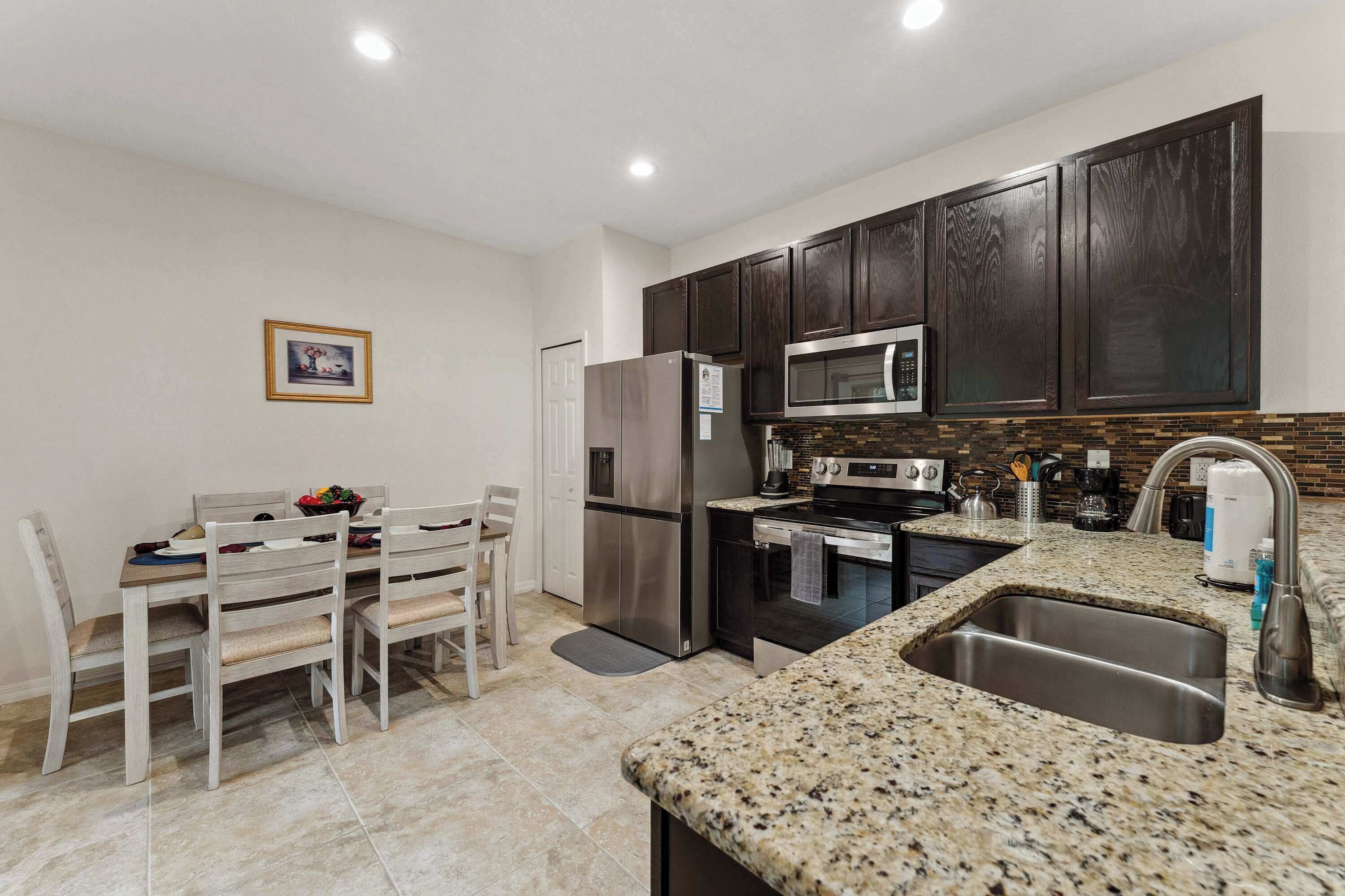 A modern kitchen with dark wooden cabinets, stainless steel appliances, and a granite countertop.