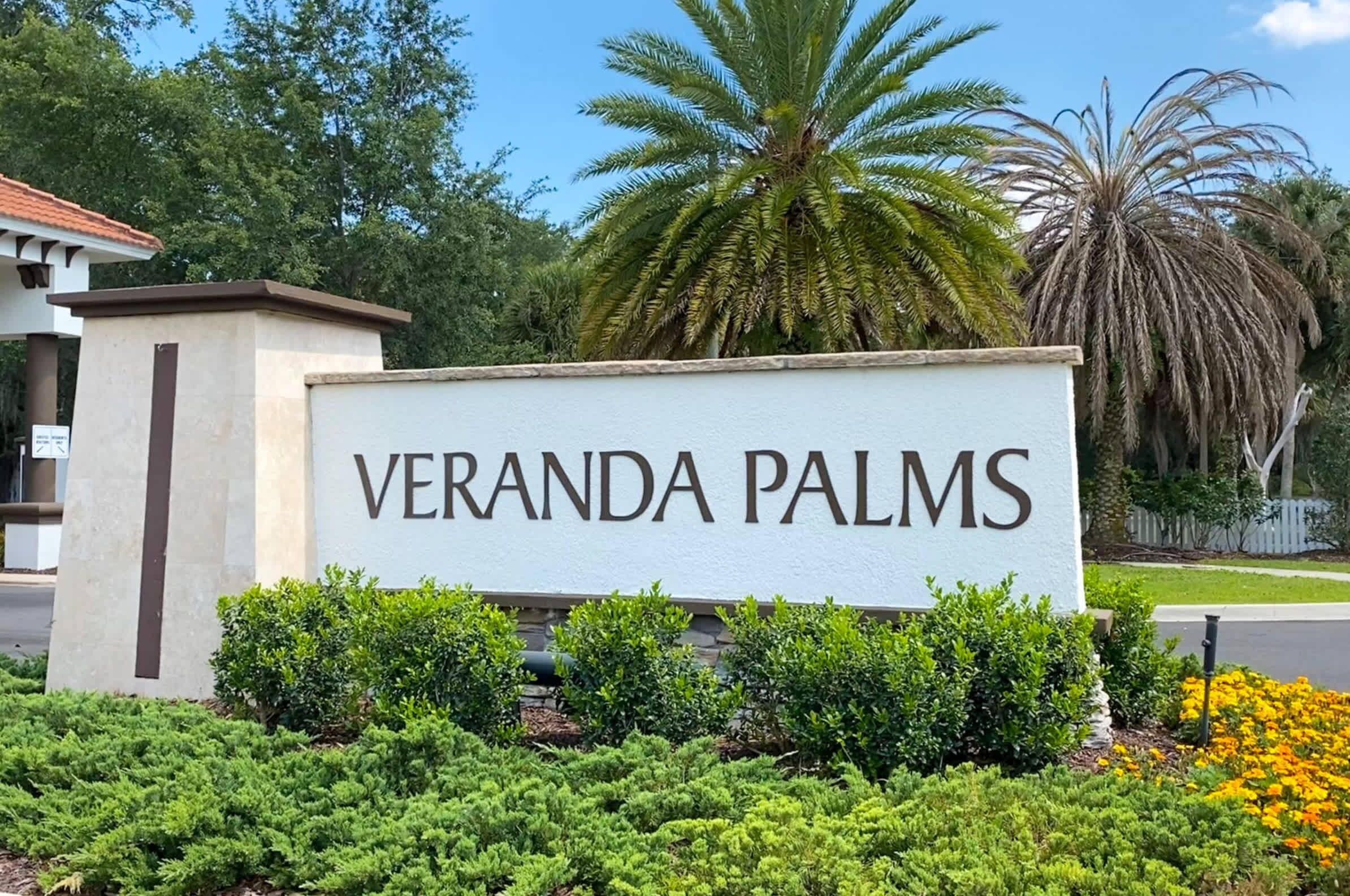 A sign for Veranda Palms with a clear view of the surrounding greenery and palm trees.