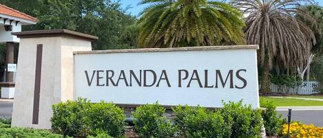 A sign for Veranda Palms with a clear view of the surrounding greenery and palm trees.