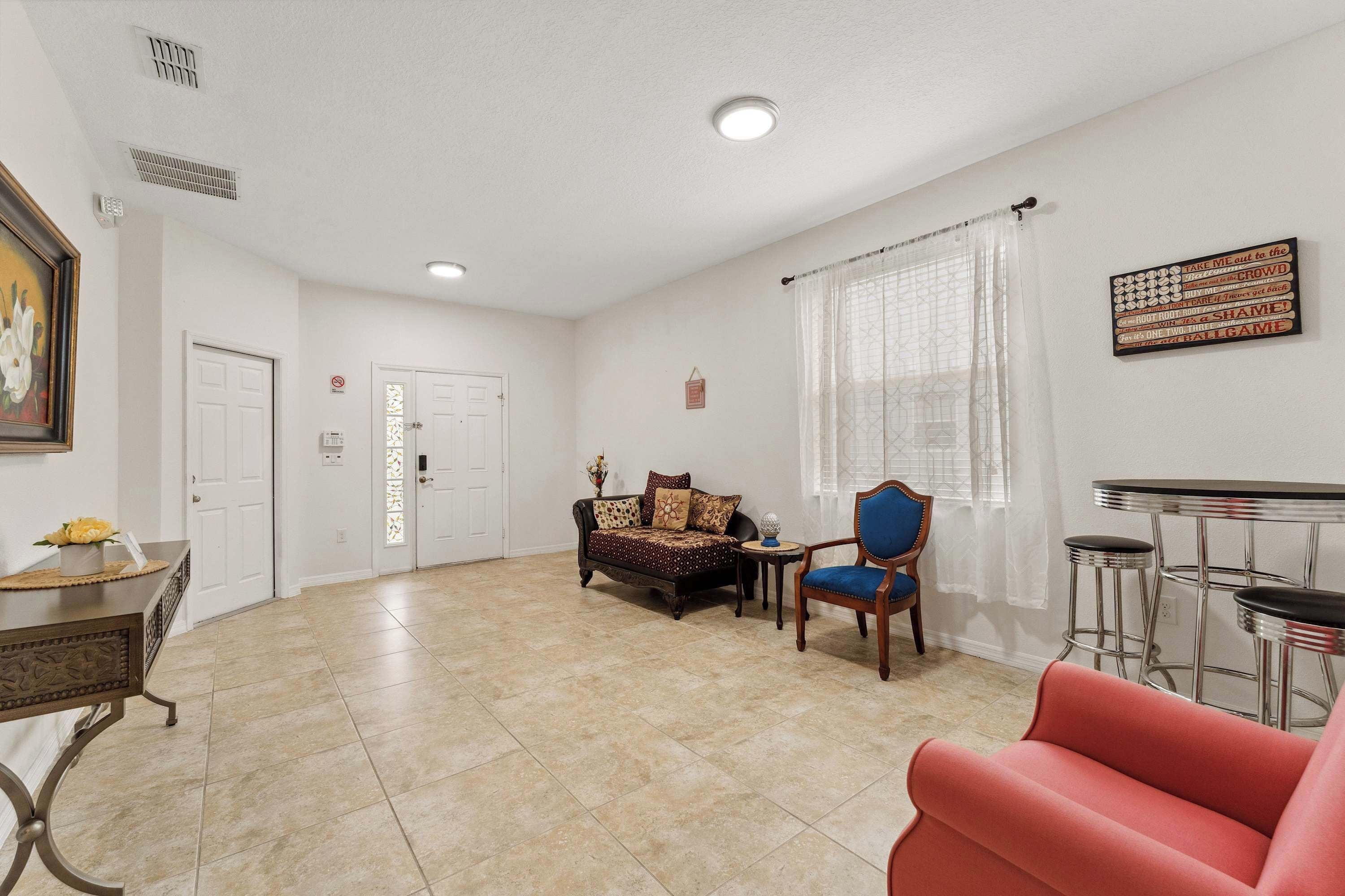 A spacious living room with a sofa, a chair, a small table, and a bar area.