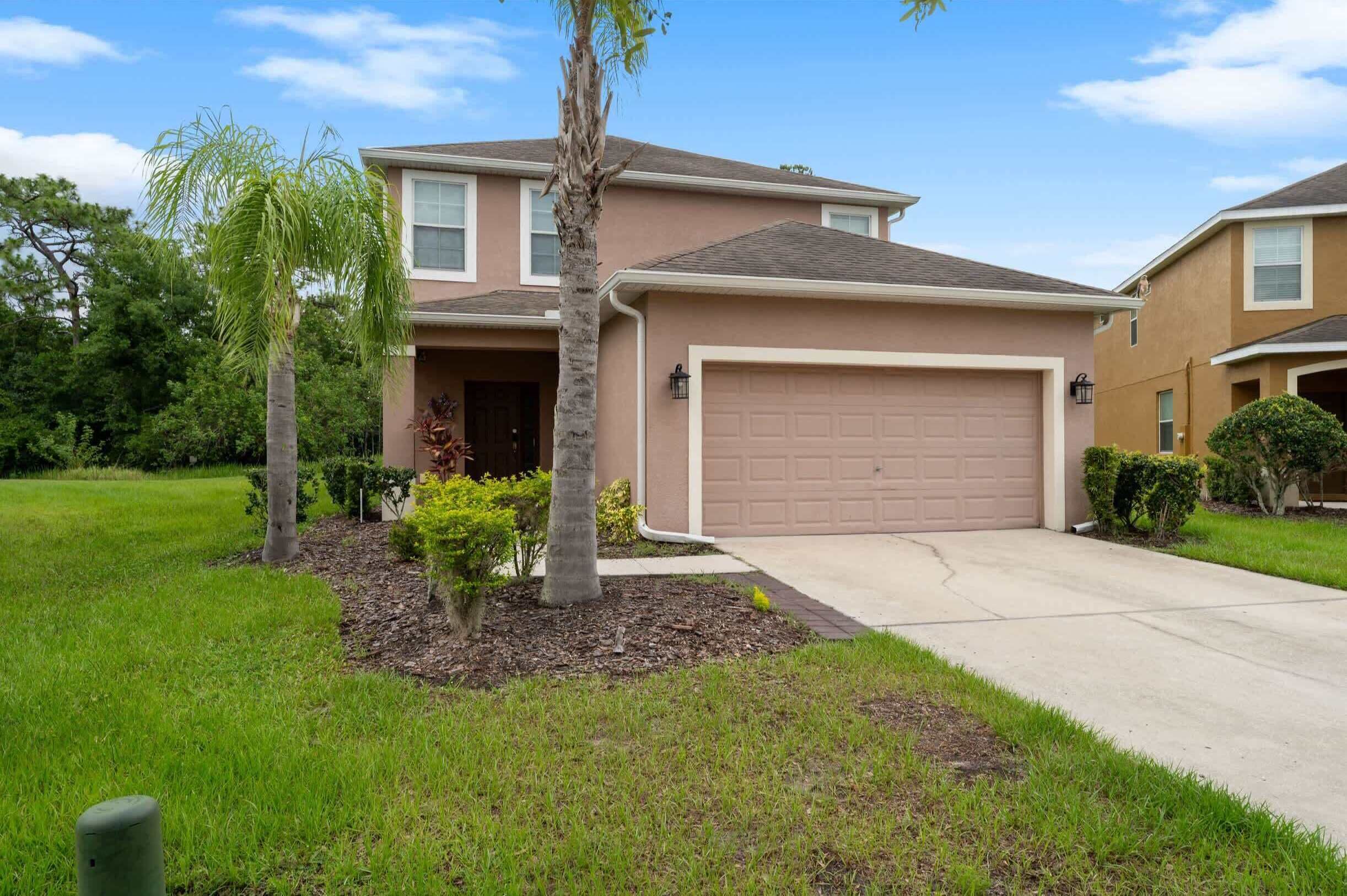 A two-story house with a garage, a driveway, and a well-maintained lawn.