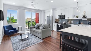 A modern kitchen with white cabinets, a black refrigerator, and a microwave. There is a dining area with a white table and black chairs. - Chic Condo Minutes to Downtown, Gruene, & More (New Braunfels)