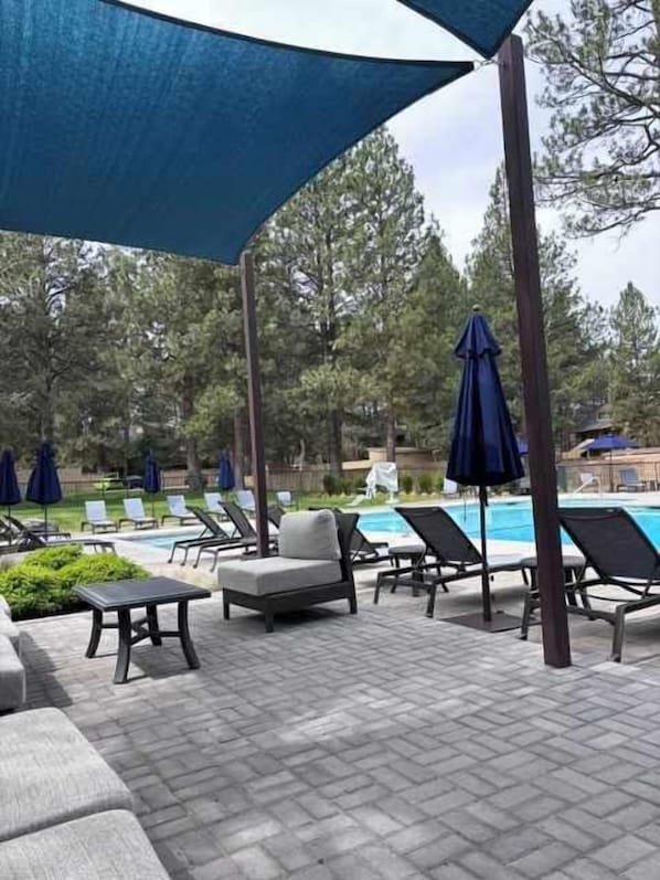 A poolside area with lounge chairs, umbrellas, and a pool. - Ponderosa Vista Resort Condo! (Bend)