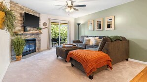 A living room with a fireplace, a sofa, a coffee table, and a ceiling fan. - My Kind of Getaway - Chic 2 Bdr! (Branson)