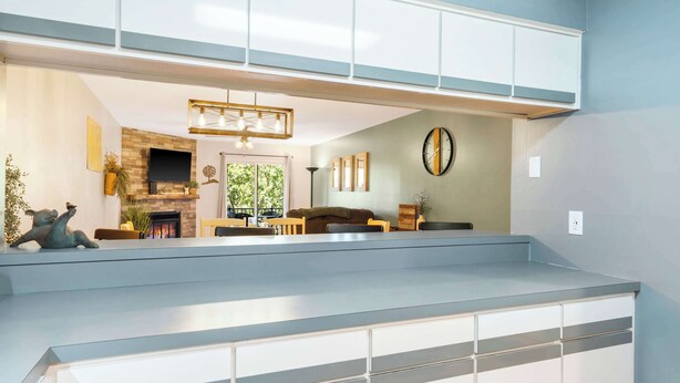 A modern living room with a fireplace, a flat-screen TV, and a dining area with a high ceiling and built-in cabinets. - My Kind of Getaway - Chic 2 Bdr! (Branson)