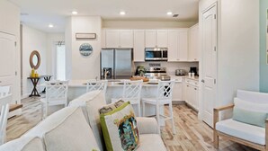 A modern kitchen with white cabinets, a stainless steel refrigerator, and a microwave. - Mint to Be (Kissimmee)