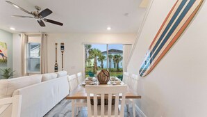 A dining area with a wooden table, white chairs, and a ceiling fan. - Mint to Be (Kissimmee)