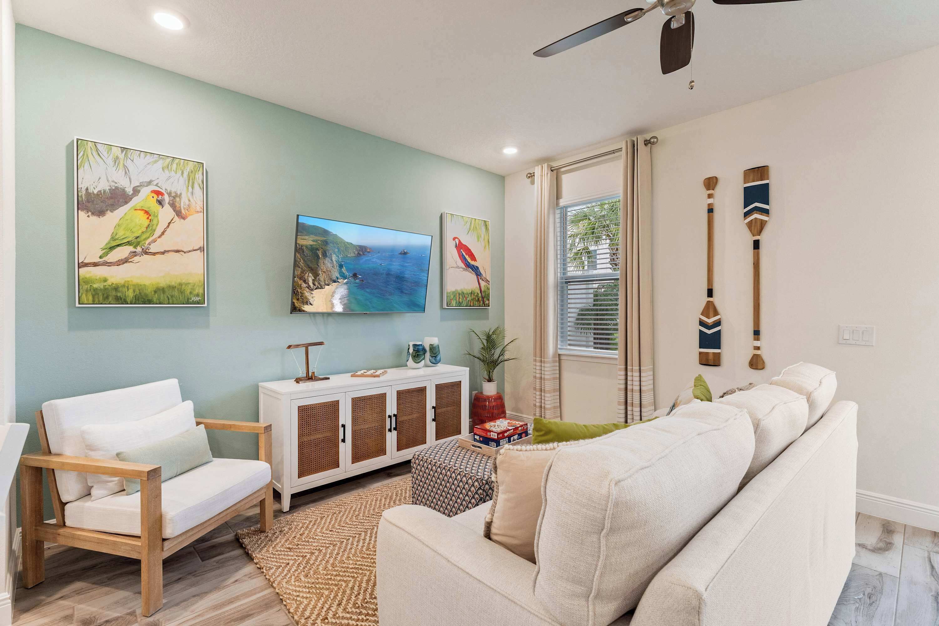 A living room with a sofa, a chair, a cabinet, and paintings on the wall.
