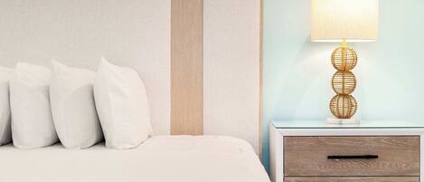 A neatly made bed with white bedding and pillows, a bedside table with a lamp, and a wall with a textured panel.