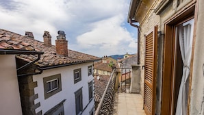 A narrow balcony with a tiled floor, a metal railing, and a view of adjacent buildings with traditional architecture.