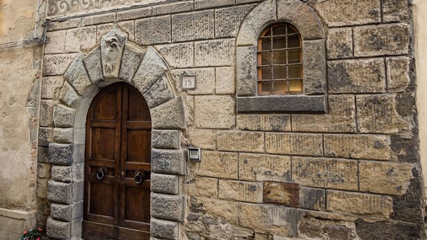 A stone building with a large wooden door and a small window.