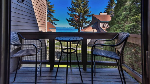 A covered outdoor area with a table and chairs, overlooking a body of water and trees.