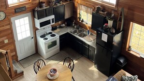 A cozy cabin-style kitchen with wooden walls, a dining table, and a sofa. - Welcome to The Fox Farm cabin  (Genoa)