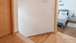 A room with a wooden door, a small window, and a bed with white bedding.