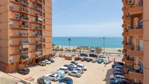 A multi-story parking lot with cars, a beach, and ocean in the background. - Marina Beach in Fuengirola (Fuengirola)